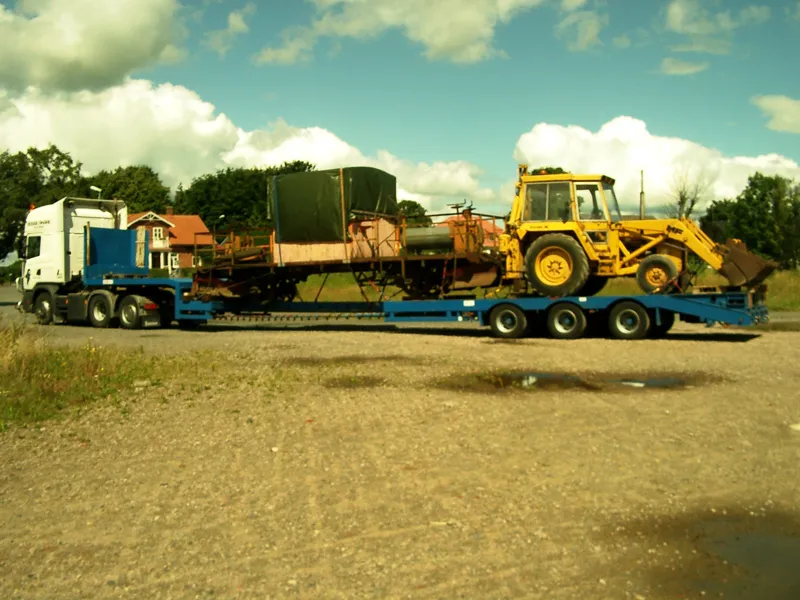 Lågbäddstrailer lastad med en gul hjullastare och en maskin