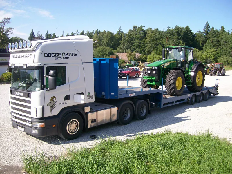 Bosse Åkares Scania med en grön traktor på lågbäddstrailern