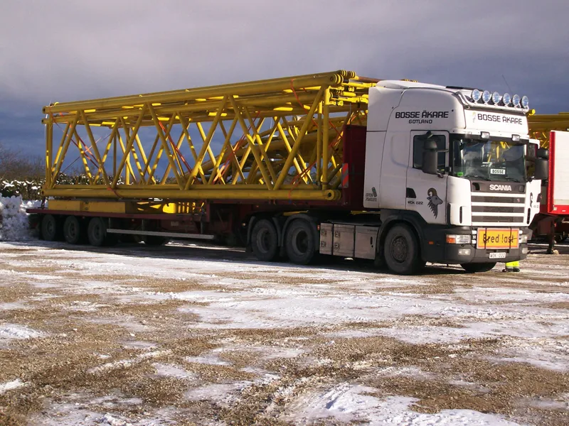 Lastbil med ett gult stålfackverk lastat på trailern
